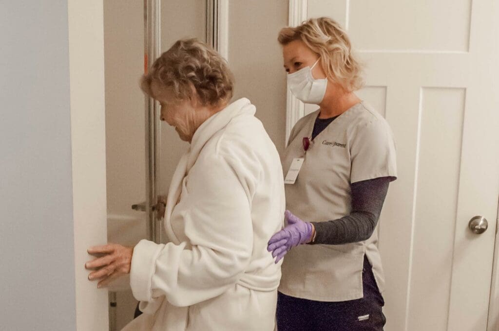Caregiver helping older lady step into shower