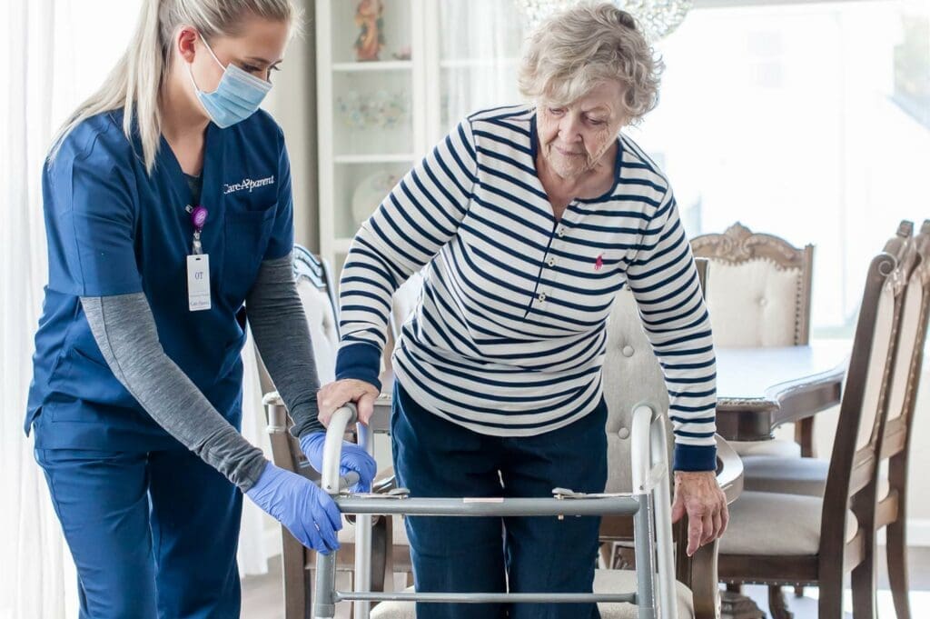 Therapist helping patient walk in home